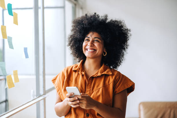 istock Pensive businesswoman holding a smartphone in a creative office 1423659636
