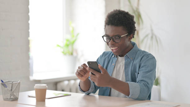 istock Successful Young African Man Celebrating on Smartphone 1423660939