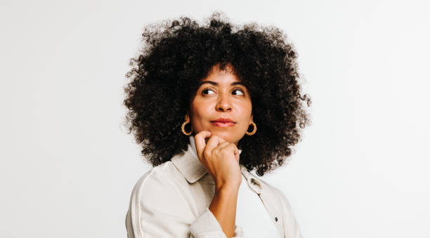 istock Thoughtful woman with curly hair standing against a studio background 1423661162