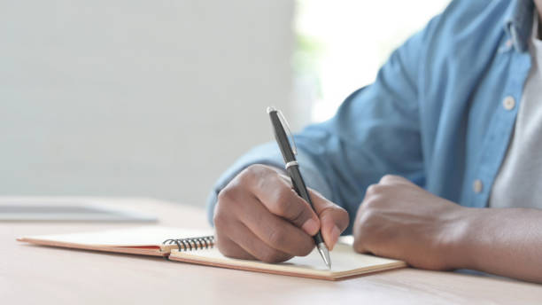 istock Close Up of Young African Man Writing on Notebook 1423664000