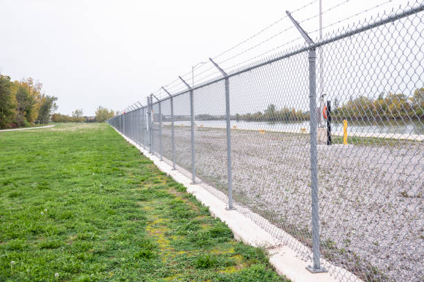 運河の岸壁に沿ったチェーンリンクフェンス - razor wire ストックフォトと画像