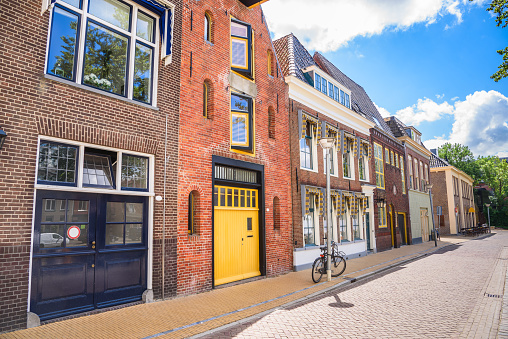 Row of historic Dutch architecture converted in residential buildings along a cobbled street in a city centre on a sunny summer day. Groningen, Netherlands.
