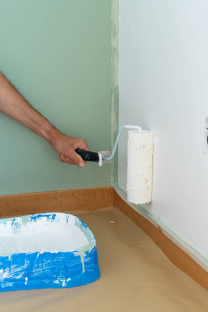 istock Man's hand painting the wall white. Copy space. 1423674610