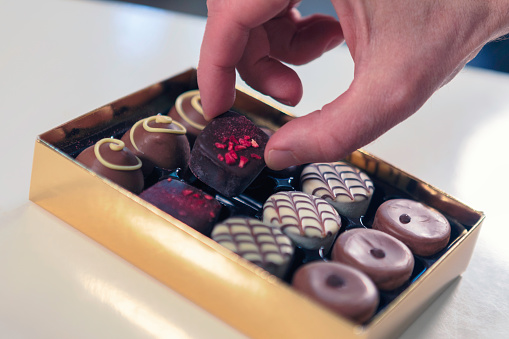 Close up of a person taking a chocolate truffle from a box.