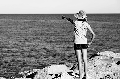 young girl with big straw hat by the sea during summer vacation