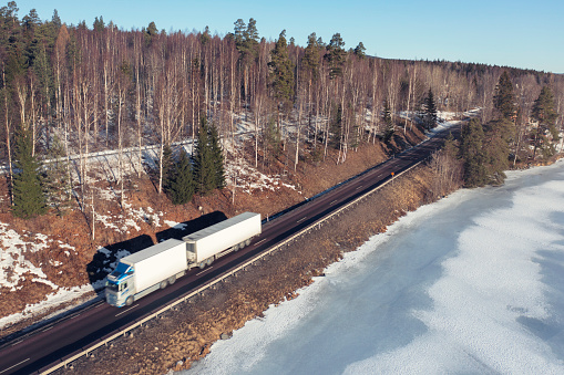Aerial view of a truck on a highway in a late winter landscape in the Dalarna region of Sweden.