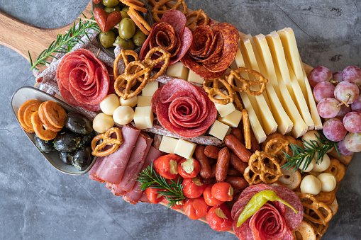 Cutting board with ham, salami, cheese, cracker and olives on a wooden board. View from above.