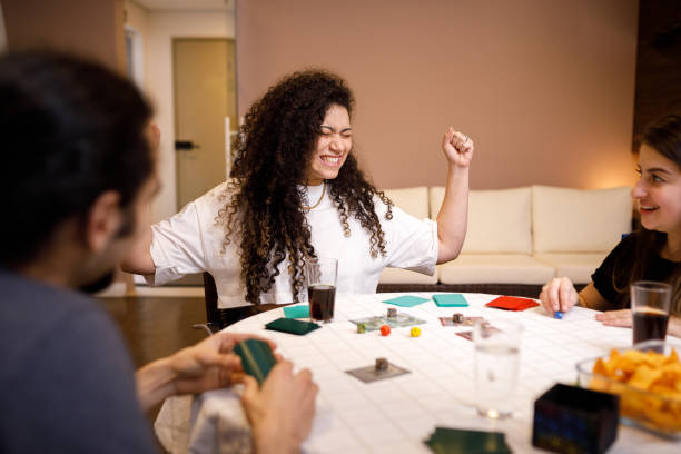 garota de cabelo encaracolado celebrando a vitória no jogo - board game success victory winning - fotografias e filmes do acervo