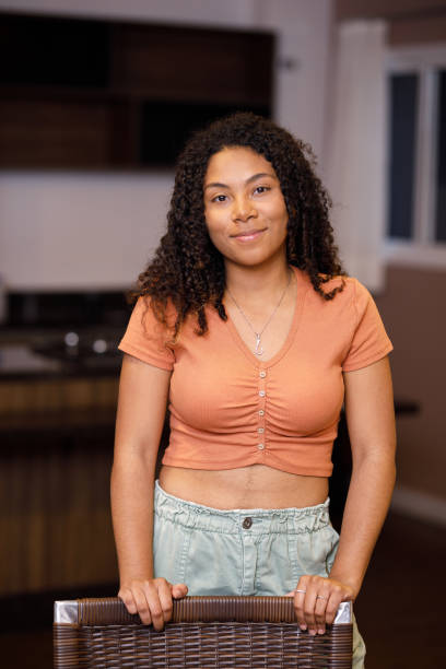 istock Curly haired young woman smiling while holding a chair 1423681206