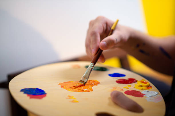 istock A close up of a handsome painter with a manbun using many colours to paint on his new canvas 1423684905
