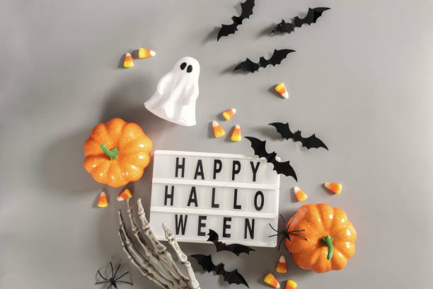 istock Happy Halloween lightbox sign board with pumpkin, bats and candy on a grey background 1423687807
