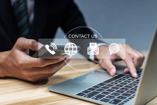 istock Contact us. business people hand using laptop computer with virtual graphic icon diagram on desk at office, digital marketing, work from home, business finance, internet network technology concept 1423693171