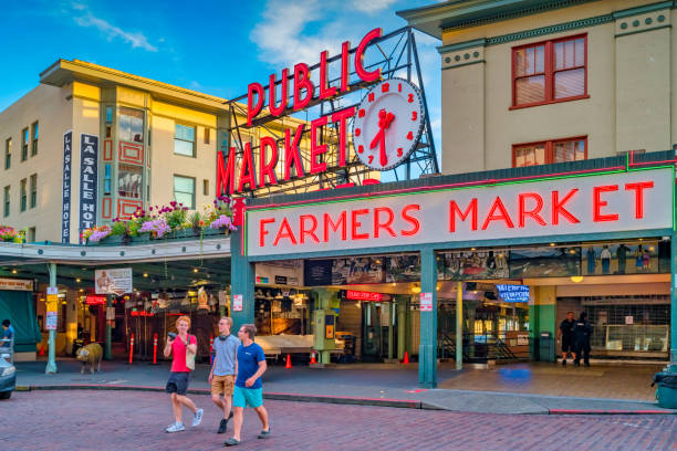 Seattle Pike Place Market Street People cross street in front of the landmark Pike Place Market in downtown Seattle, Washington, USA at sunset. pike place market stock pictures, royalty-free photos & images