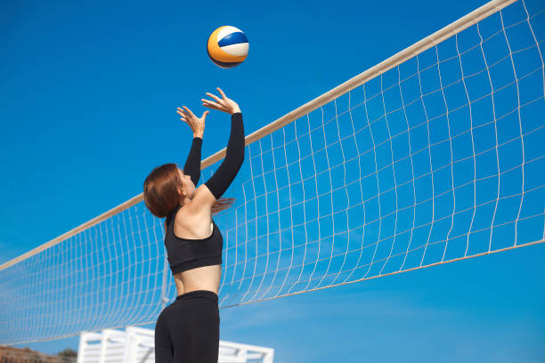 sporty young women playing beach volleyball match. professional female volleyball player hit the ball over the net. summer sports concept - beach body ball volleyball imagens e fotografias de stock