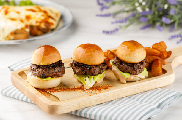 istock Three sandwiches with beef patties and wedges isolated on cutting board on table side view of arabian fastfood 1423705520