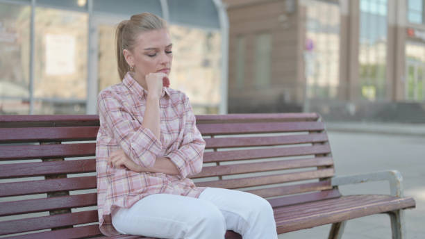 istock Tired Young Woman Sleeping while Sitting Outdoor on Bench 1423709574