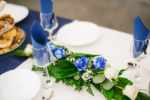 Blue roses and blue decoration on the table at the wedding