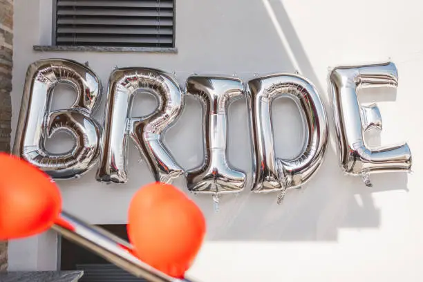 Photo of BRIDE - word made from silver gold foil balloons. party or holiday décor concept for bride at home