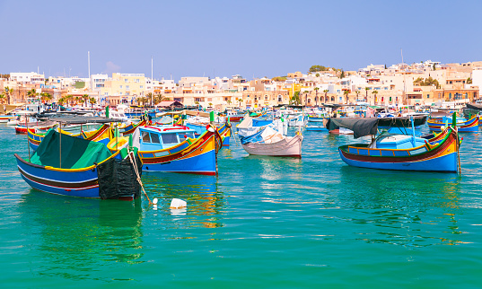 Colorful traditional Maltese fishing boats are moored in Marsaxlokk port, Malta