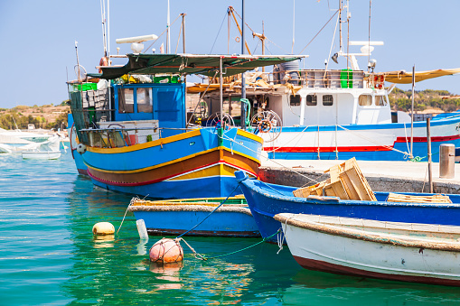Colorful traditional Maltese fishing boats are moored in Marsaxlokk harbour, Malta