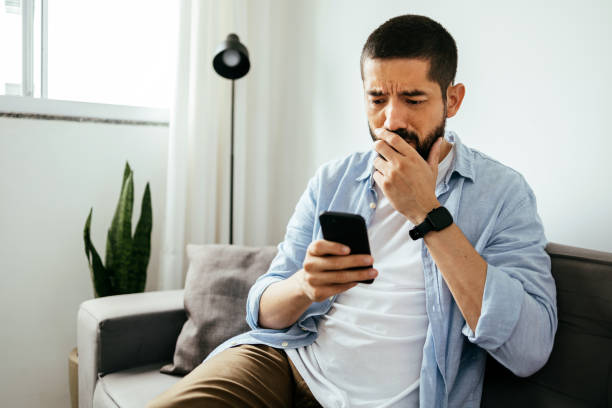 istock Sad man checking smartphone sitting on a sofa at home 1423714191