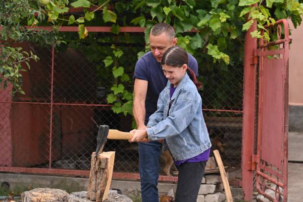 istock Daughter and father chop wood with an axe. 1423715286