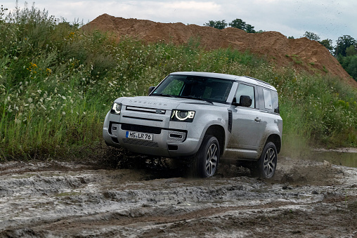 Ahlbeck, Germany - 26th July, 2022: Land Rover Defender driving on muddy road. This vehicle is used to get in extremely hard areas.