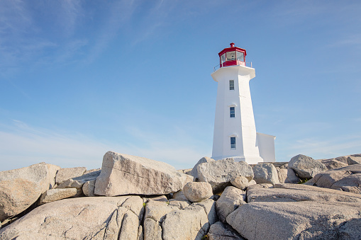 Landmark lighthouse at Peggy's Cove, Nova Scotia on a summer morning with blue skies.