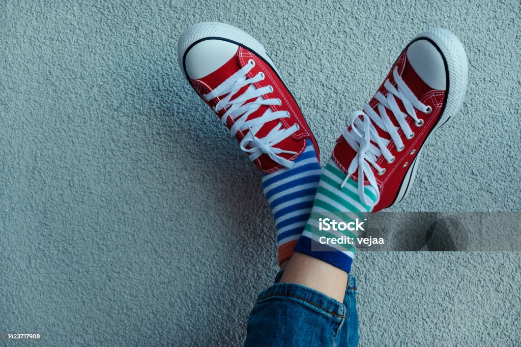 Kid wearing different pair of socks. Child legs up in mismatched socks on gray background. Odd Socks day, Anti-Bullying Week. Down syndrome awareness concept Kid wearing different pair of socks. Legs in mismatched socks on gray background. Odd Socks day, Anti-Bullying Week. Down syndrome awareness concept Sock Stock Photo