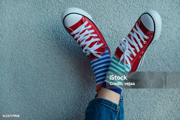 Kid Wearing Different Pair Of Socks Child Legs Up In Mismatched Socks On Gray Background Odd Socks Day Antibullying Week Down Syndrome Awareness Concept Stock Photo - Download Image Now