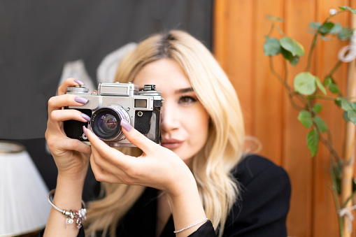 Young woman holds an analog camera and looks through the viewfinder