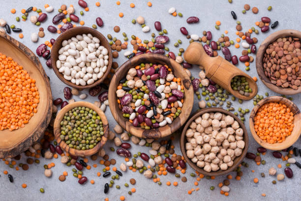 Different beans, lentils, mung, chickpeas in wooden bowls Top view of different beans, lentils, mung, chickpeas in wooden bowls for tasty meals on grey concrete background bean stock pictures, royalty-free photos & images