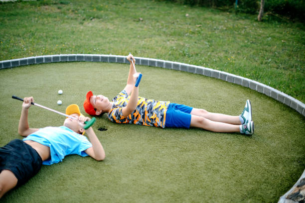 garçons jouant au mini-golf - golf golf swing putting cheerful photos et images de collection