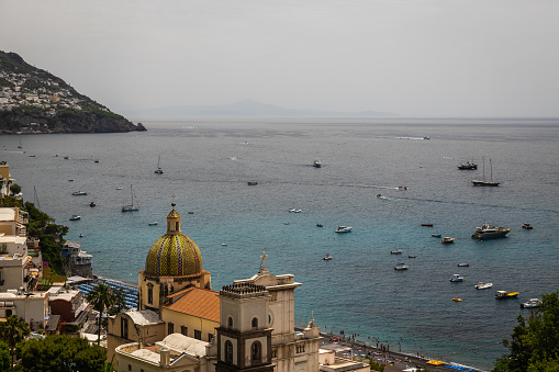 View of the coastline, the Amalfi coast, the town of Capri and the Faraglioni, located in the of the Island of Capri in the Tyrrhenian Sea in Italy. Boats are floating next to them, This are rock formations eroded by the wind and water.
