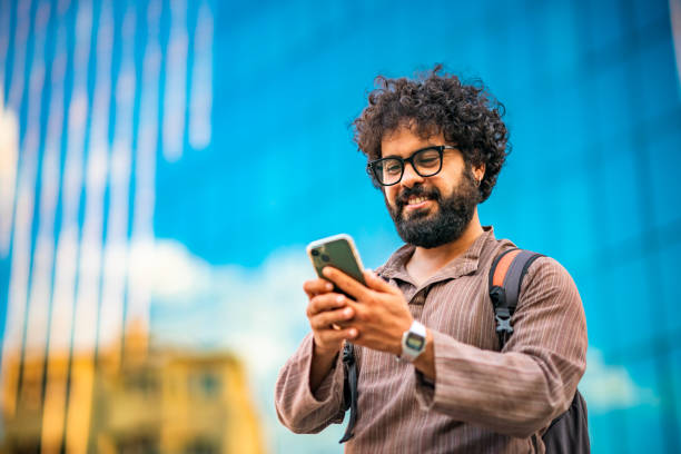 Middle Eastern Man using mobile phone outdoors in city stock photo