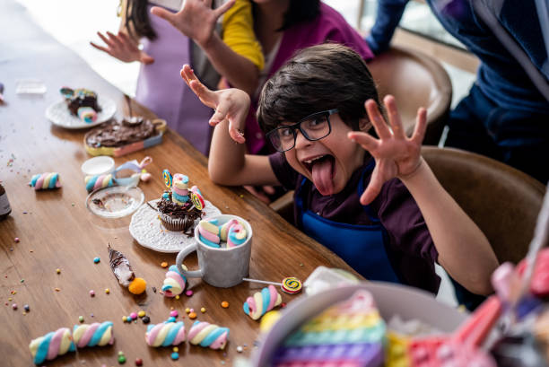 портрет мальчика, играющего со сладостями в детский день дома - cupcake cake birthday candy стоковые фото и изображения