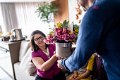 Wife receiving a gift box with a bouquet from her husband at home