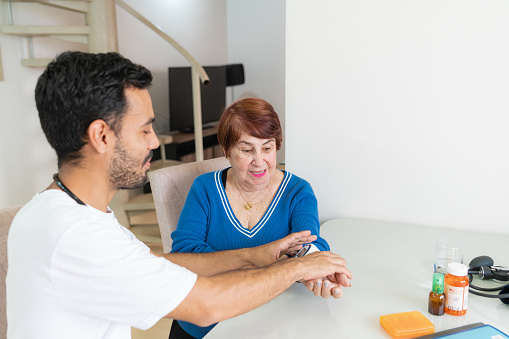 Caregiver checking lady blood pressure. Health and wellness concept