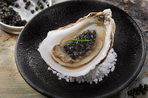 Close Up of Server with Tray of Fresh Shucked Oysters with Lemon Wedges Served as Appetizer. tray with oysters in female hands