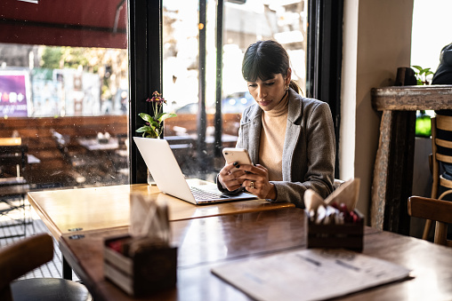 Young business woman using mobile phone at coffee shop