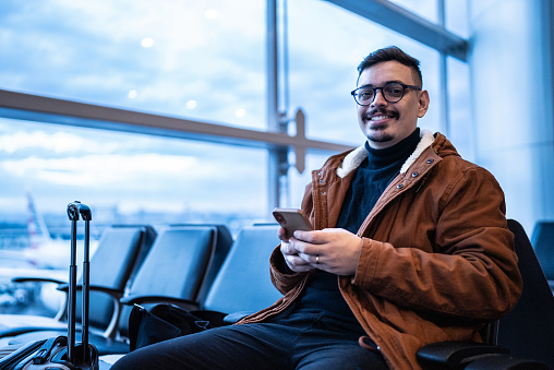 Portrait of a young man using the mobile phone in the airport