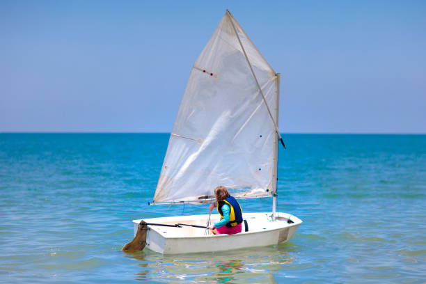 Child sailing. Kid learning to sail on sea yacht. Healthy water sport for school kids. Yachting class for young sailor. Children on boat. Family summer vacation on tropical island. Beach activity.