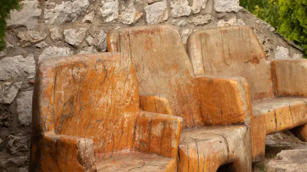Old wooden ancient chairs in vintage style in front of a stone wall. A close-up. Authentic antique furniture design.