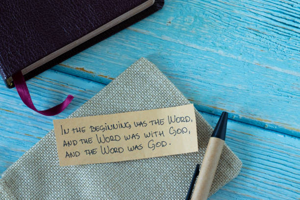 Handwritten biblical text on a note with pen and closed Holy Bible Book on blue wooden background stock photo
