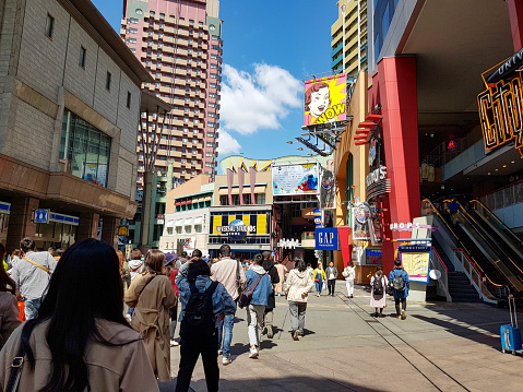 Osaka, Japan on April 9, 2019. This is a rear view photo of people walking into Universal Studios Japan on a sunny day.
