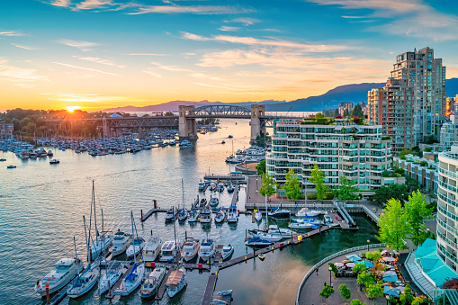 A sunny mid 2020 aerial shot of downtown Vancouver, Yaletown, a marina, North Shore mountains, BC Place, False Creek and the Cambie bridge.