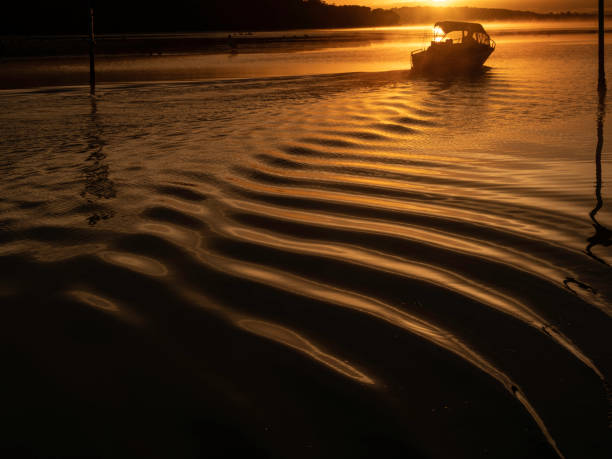 Fishing boat in silhouette  at sunrise Small fishing boat leaving Denmark river mouth Western Australia at sunrise glittering sea stock pictures, royalty-free photos & images