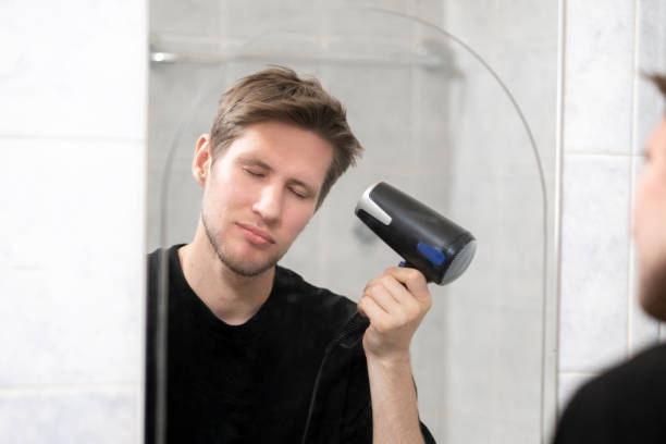 istock young guy using hair dryer, daily morning routine 1423791751