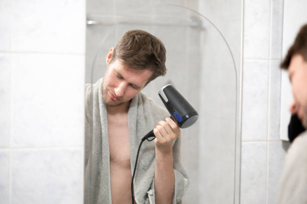 istock young guy using hair dryer, daily morning routine 1423791755