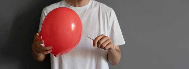 needle blowing balloon, as the concept of economy risk and crisis stock photo